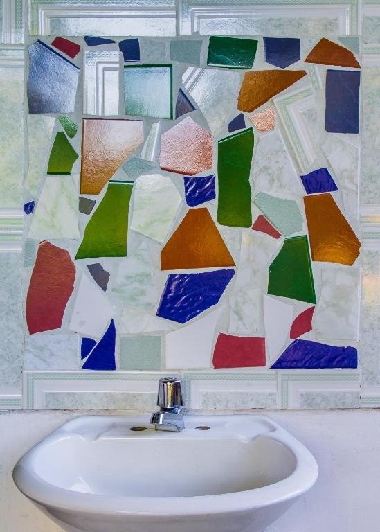Mural artesanal en mosaico de vidrio colorido sobre lavamanos